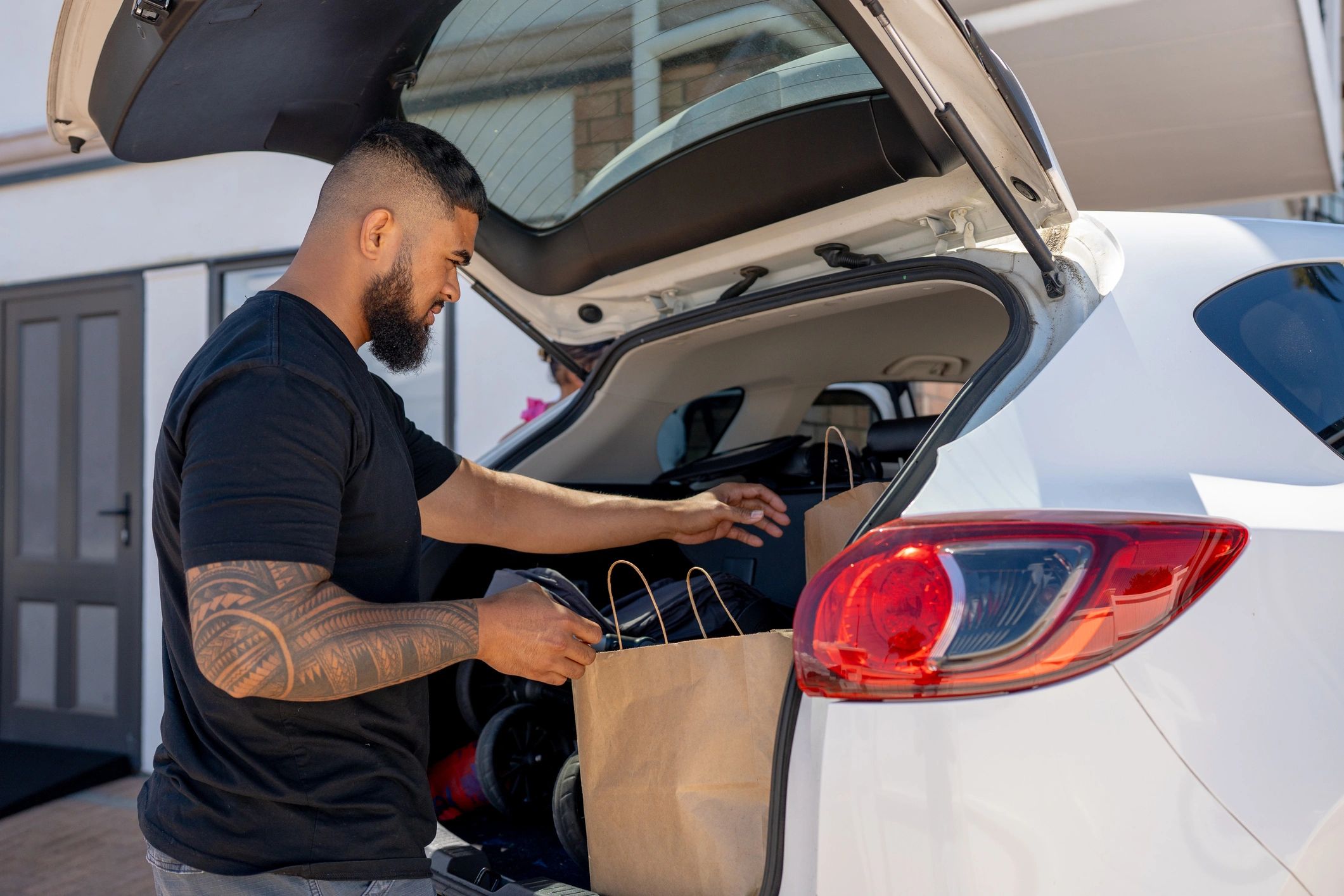 About Delivery driver unloading grocery bags from a vehicle