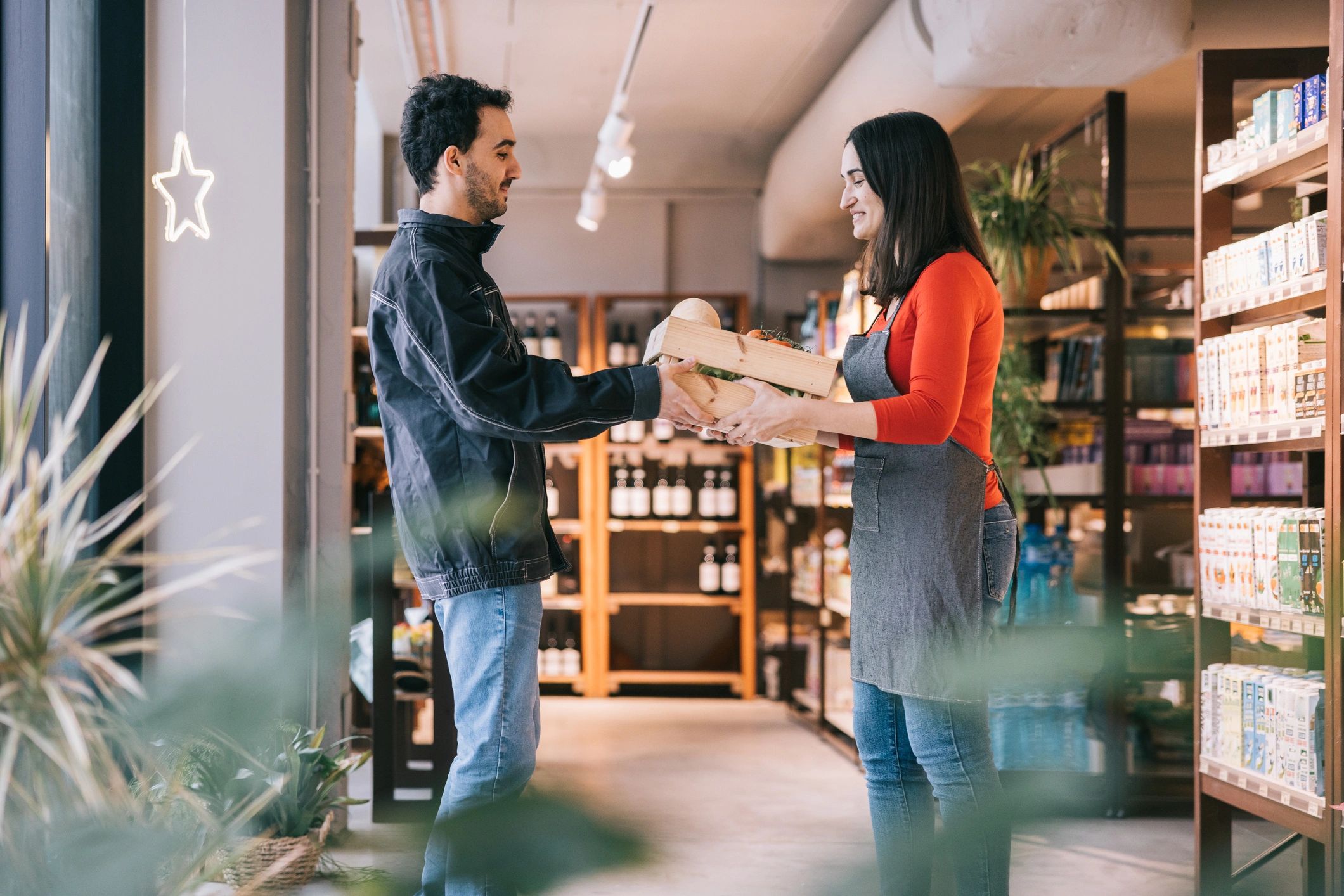 About Courier handing over a crate of fresh vegetables in a shop